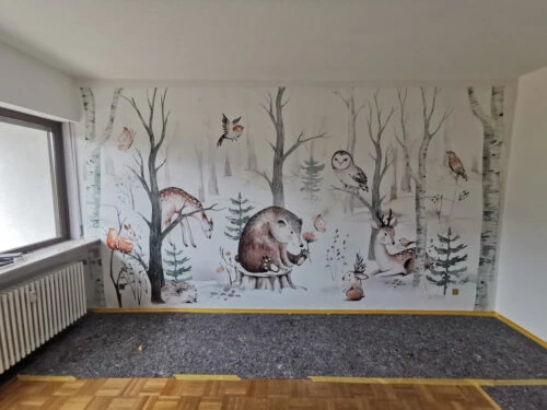 Fototapete mit Bär, Reh, Eule und weiteren Waldtieren zwischen Bäumen an einer Wand in einem hellen Raum.